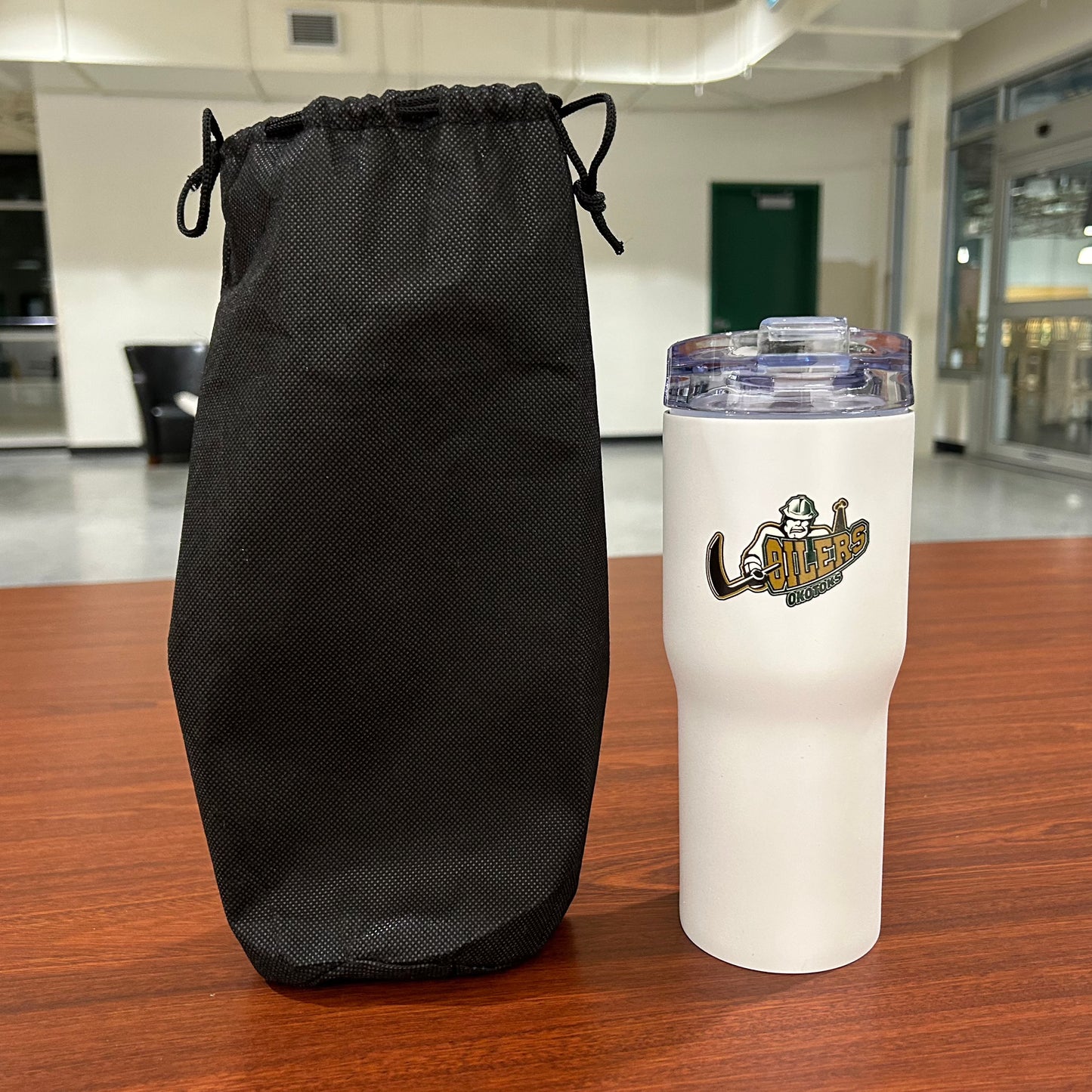 Oilers travel mug next to black carrying sleeve.