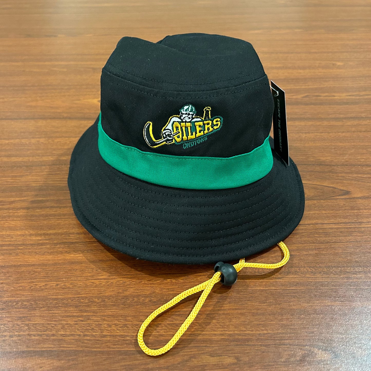 Black bucket hat with a green stripe underneath the Oilers' primary logo. The hat also has a yellow drawstring.
