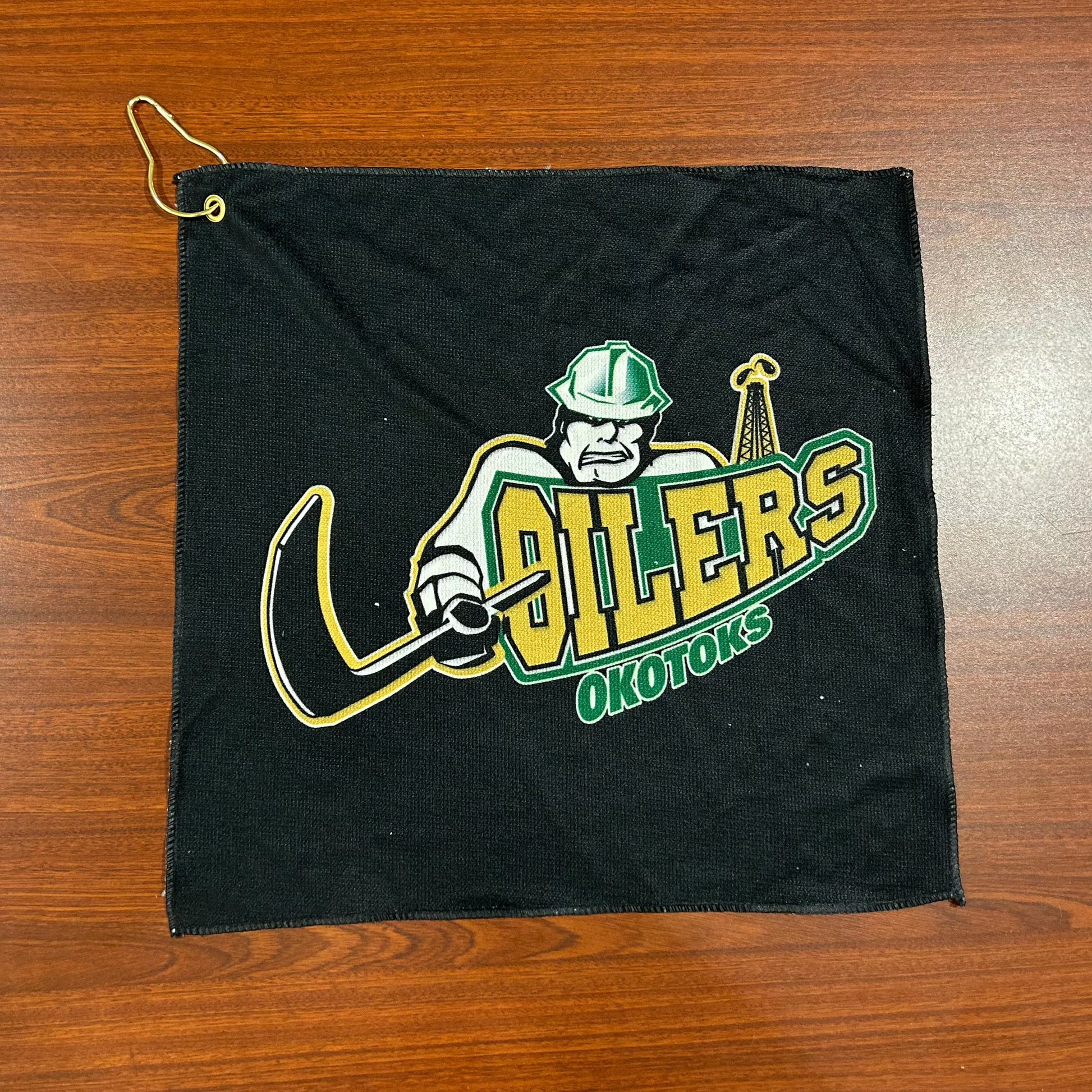 Black golf towel with the Oilers' primary logo. The towel can be attached to a golf bag with the gold clip in the top-left corner.